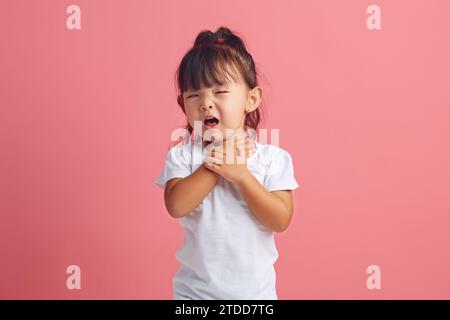 Frustrated little girl keeping throat and coughs having painful feelings or asthma attack.  Stock Photo