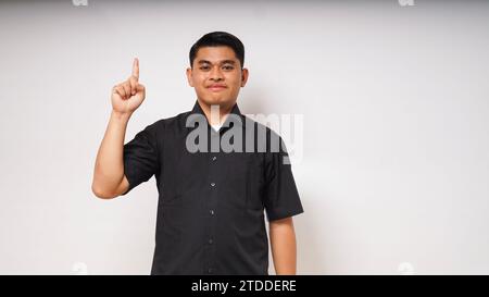 Smiling happy Young Asian man pointing both hands up on white background. studio shot Stock Photo