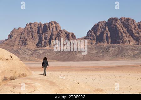 Man walking on rock formation with desertic landscape behind Stock Photo