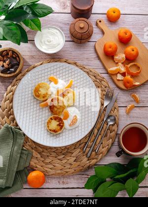 homemade cheesecakes on a plate with sauce and tangerines Stock Photo