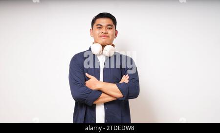 Happy young Asian man wearing wireless headphones listening to music from smartphone studio shot isolated on white background Stock Photo