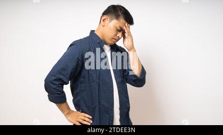 Asian young man showing in pain expression while touching his head Stock Photo