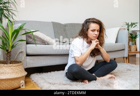 Sad woman sitting on floor at home. Mental illness. Stock Photo