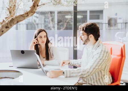 Two coworkers collaborating in an office, discussing project details, sharing ideas, and working towards business success. Stock Photo