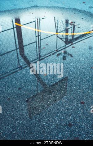 Reflection of basketball board and hoops in a pond on outdoor streetball court, selective focus Stock Photo