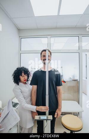 Medical professional in an office measuring patient height in a positive atmosphere. Stock Photo