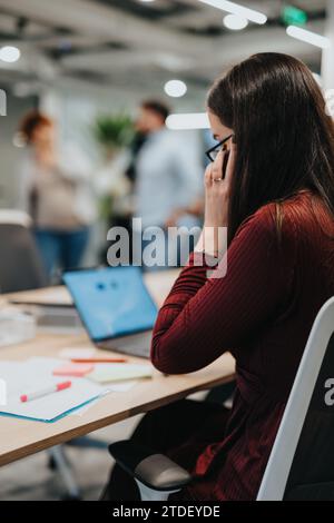 Young adult businesswoman collaborating with colleagues in a corporate office. Stock Photo