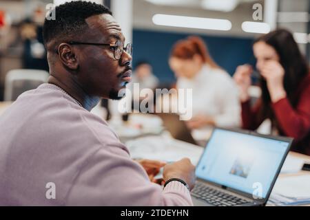Colleagues in a corporate office working together on data analysis and market research using laptops, promoting teamwork and collaboration. Stock Photo