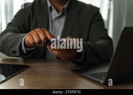 businessman working uses a mobile texting cell phone to contact us business and connect on a desk computer work job at workplaces Stock Photo