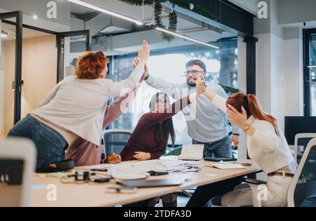 Multicultural team celebrates successful project with smiles and happiness. Stock Photo