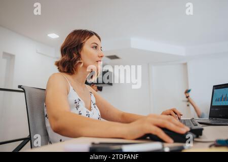 Businesswoman analyzing financial and sales reports using technology for company growth. Stock Photo