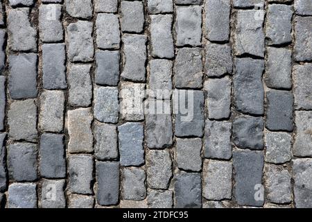 Dark grey cobblestone pavement from old smooth stones as background top view close up Stock Photo
