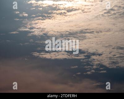 Fluffy gray clouds floating scattered across the sky at sunrise Stock Photo