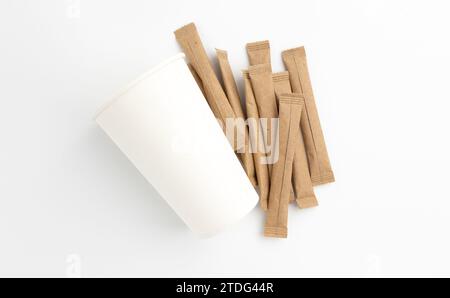 sugar sticks and paper cup, sugar in paper kraft packaging, mock up for design isolated on white background with clipping path Stock Photo