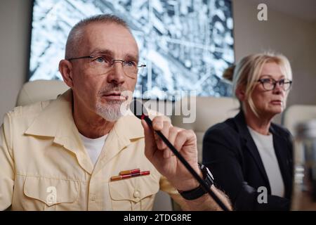 Military man speaking in microphone while having conference with his colleagues Stock Photo