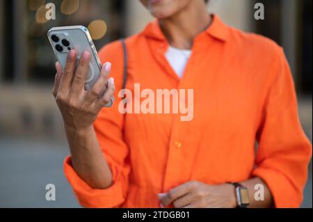 Unrecognizable woman standing outdoor with smartphone in hands. Stock Photo