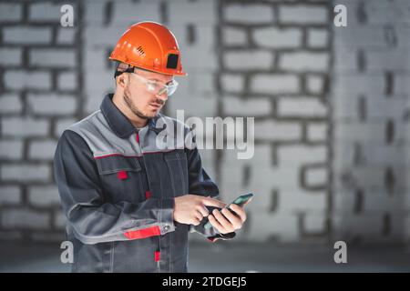 Caucasian male construction worker in overalls using smartphone Stock Photo