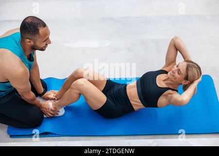 Woman with blonde hair in excellent shape doing sit-ups with her boyfriend, Stock Photo