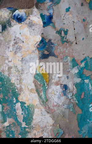 Abstract, detail, pattern of a section of multi-colored, turquoise and white peeling paint layers on an old stone exterior wall of a residence in Jeru Stock Photo