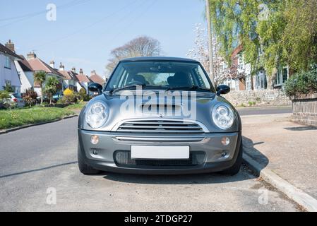 A Mini Cooper S from 2005 is parked in front of a residential house on the street. Stock Photo