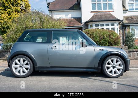 A Mini Cooper S from 2005 is parked in front of a residential house on the street. Stock Photo