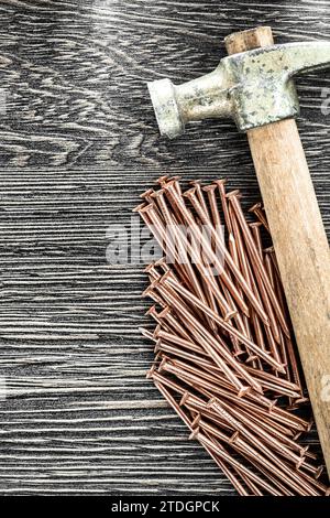 Stack of copper nails claw hammer on wooden board Stock Photo