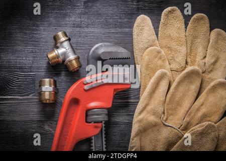 Adjustable wrench plumbing fittings protective gloves on wooden board Stock Photo