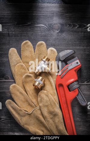 Adjustable wrench plumbing fittings leather safety gloves on wood board Stock Photo