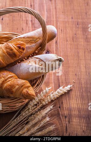 Baguettes and croissants in a wicker basket with ears of wheat Stock Photo