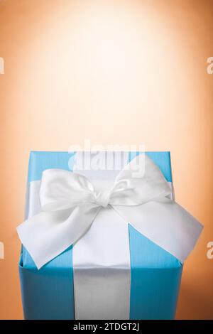 Blue gift box with white ribbon on a light brown background with Copyspace Stock Photo