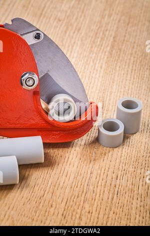 Pipe cutter with pipes on wooden plate Stock Photo