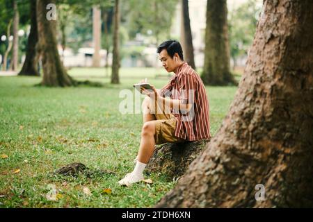 Creative young man listening to music in earbuds and drawing sketches on tablet computer Stock Photo