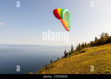 A trainer and his passenger set off from Mont-St-Pierre for a paragliding flight. Mont-Saint-Pierre, Quebec, Canada. Stock Photo