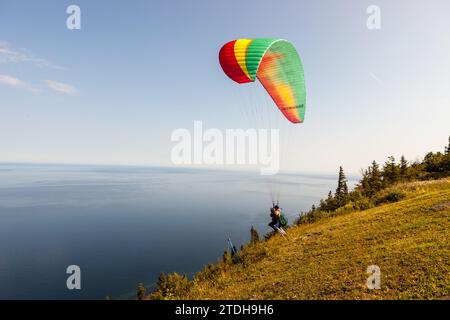 A trainer and his passenger set off from Mont-St-Pierre for a paragliding flight. Mont-Saint-Pierre, Quebec, Canada. Stock Photo