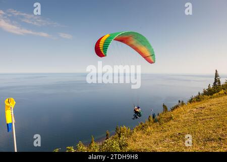 A trainer and his passenger set off from Mont-St-Pierre for a paragliding flight. Mont-Saint-Pierre, Quebec, Canada. Stock Photo