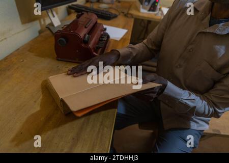 Close-up of a blind man holding a braille book resting on the table: braille reading session. Stock Photo