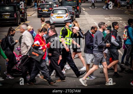 A Police Scotland Police Officer With Face Mask, Amongst Pedestrians, Crosses Hanover Street Edinburgh Scotland, United Kingdom, UK Stock Photo