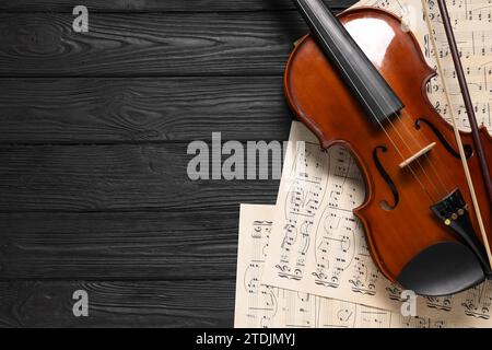 Violin, bow and music sheets on black wooden table, top view. Space for text Stock Photo