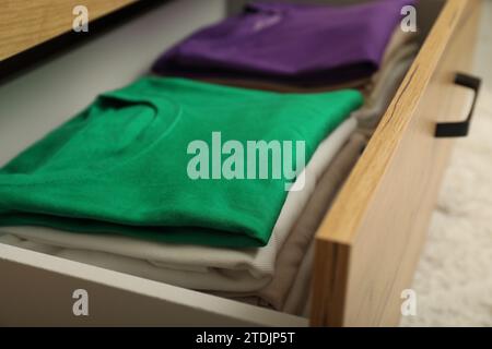 Stacks of different folded shirts in drawer, closeup. Organizing clothes Stock Photo