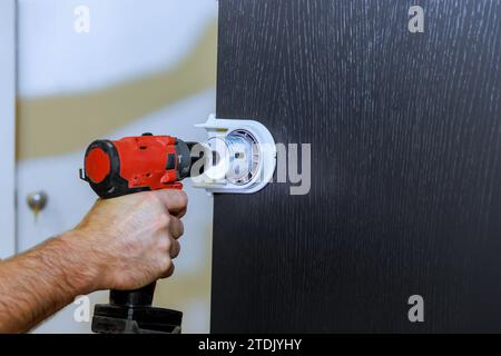 Drilling holes for lock handles in wooden doors by handyman Stock Photo