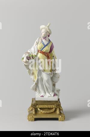 Two Chinese figures, anonymous, c. 1765 Figure of painted porcelain. On a flat square pedestal a figure is known as a 'malabar'. The woman wears a yellow top with blue edges and a fur lining. She wears a pointed hat. In her right hand she is wearing a basket with fruits, a handle basket with lid in the left hand. The pedestal is mounted on a gilded bronze pedestal. The figure is not marked. Parisporcelain Company: Meissenendigner: Meissendeigner: Meissen porcelain. bronze (metal). gilding (material) gilding Figure of painted porcelain. On a flat square pedestal a figure is known as a 'malabar' Stock Photo