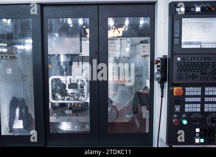 CNC machining center cutting automotive engine part. Industrial manufacturing metalwork. Stock Photo