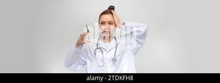 Young woman holding syringe stressed and frustrated with hand on head, surprised and angry face Stock Photo