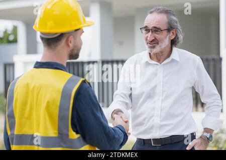 Businessman project director or real estate business owner land investor happy hand shaking with engineer foreman builder in house construction site. Stock Photo