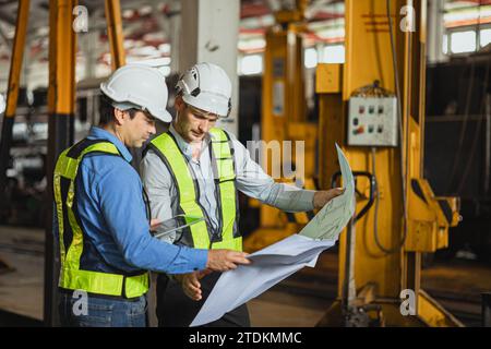 Engineer team smart young skill worker consulting supervisor working together with design floor plan in locomotive train depot workshop Stock Photo