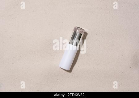 Close-up of a cosmetic bottle with a luxurious design isolated on a sandy background. Exquisite space for high-end cosmetics advertising. Flat lay. Stock Photo