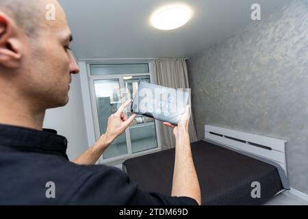 Worker with tablet computer checking alarm system indoors Stock Photo