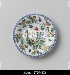 Fluted saucer with rocks, flower sprays and birds, anonymous, c. 1700 - c. 1724 Porcelain saucer with ribbed wall, partly covered with cafe-au-lait, painted in underly glaze blue and on the glaze blue, red, green, yellow, eggplant, black and gold. On the flat a butterfly and flowering plants (peony, chrysanthemum) in a rock; Four flower branches on the wall interspersed with a bird; the edge with curl; The rear is covered with a cafe-au-lait-colored enamel with three flower branches on it. Marked on the underside with a mushroom (Lingzhi) [?] In a double circle. Famle Verte. China porcelain. g Stock Photo