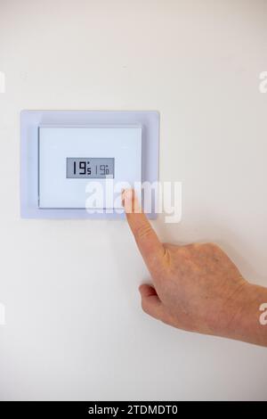 Person adjusting the temperature of their thermostat Stock Photo
