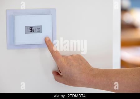 Person adjusting the temperature of their thermostat Stock Photo